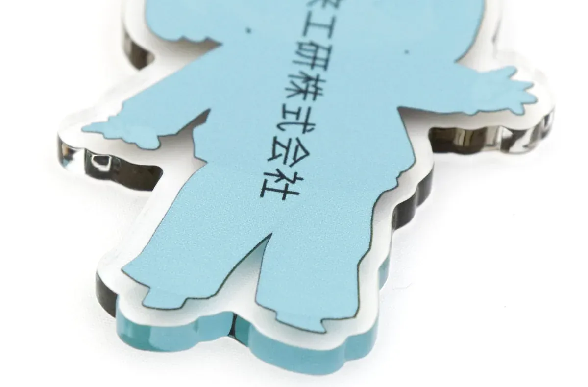 アクリルキーホルダーの裏を近くから写したもの。社名と板の厚みが見える