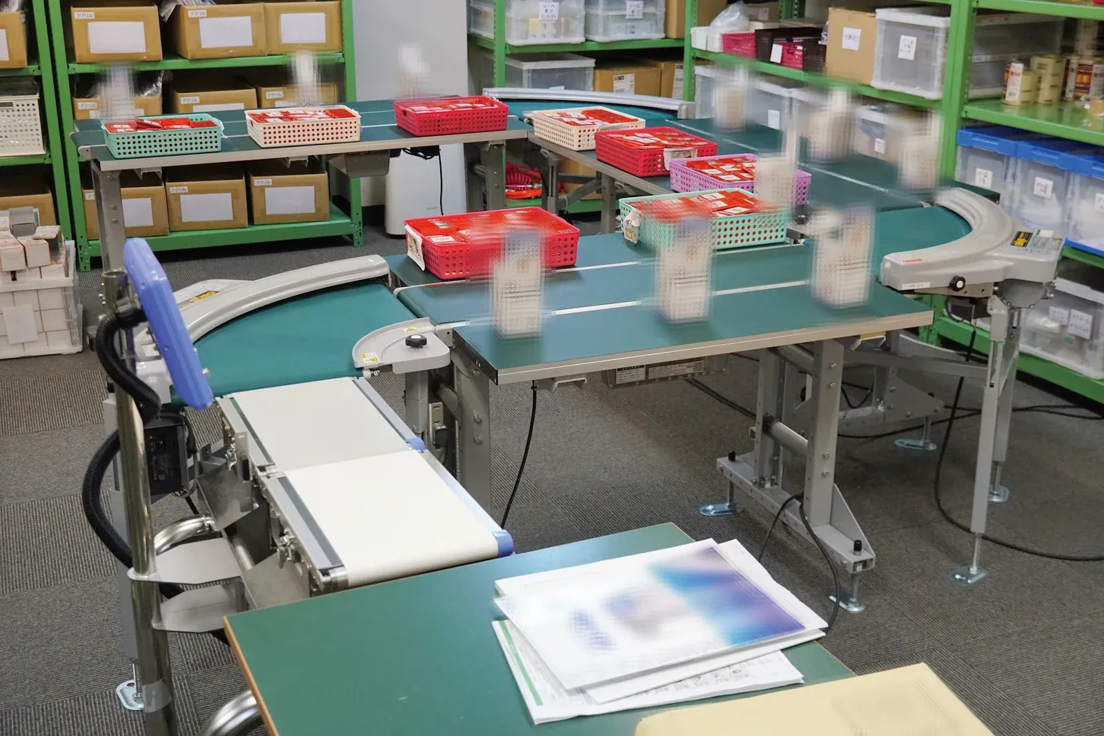 ベルトコンベアが並ぶ包装ライン。かごに入った製品が流れている（福岡の自社工場）